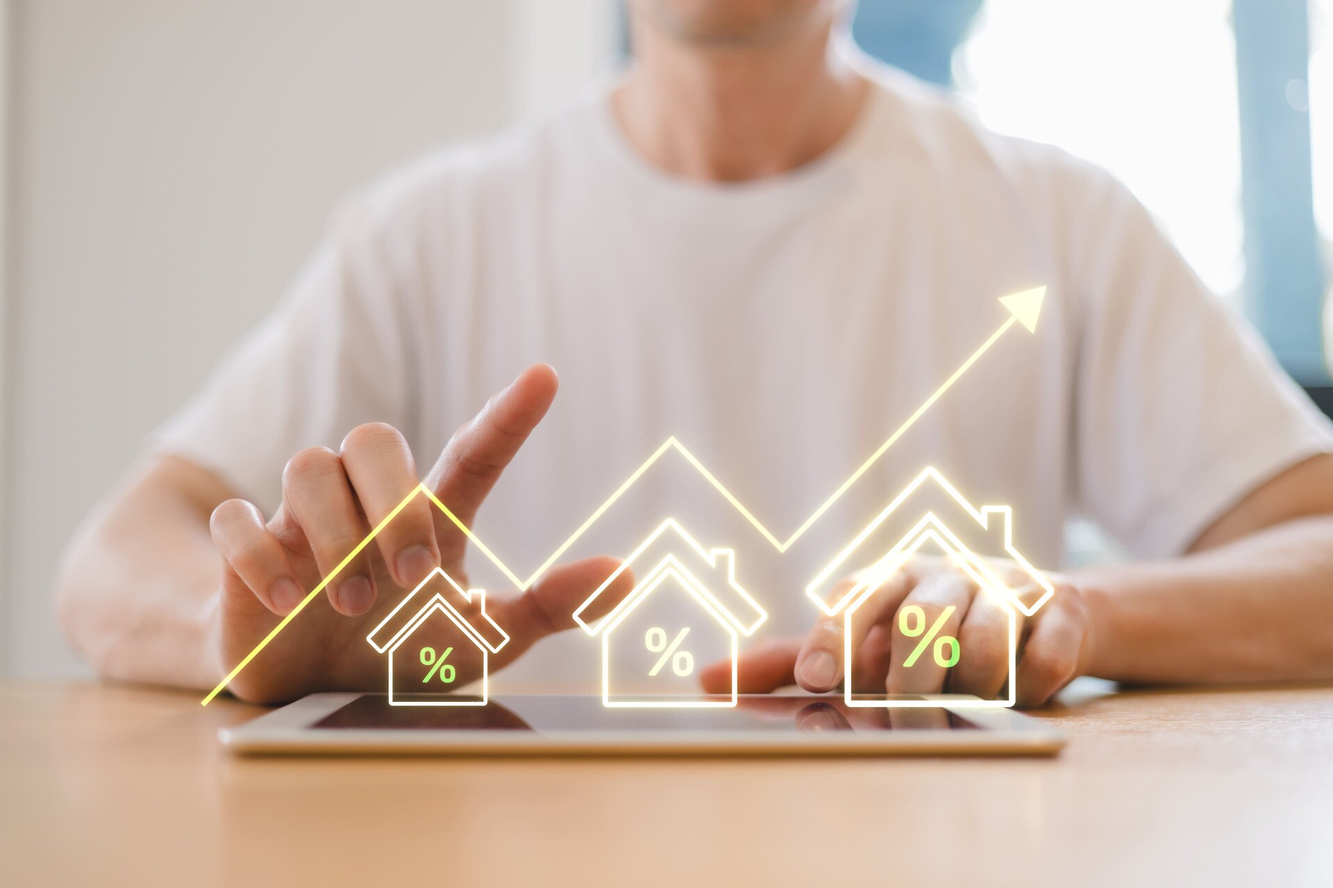 Mann sitzt am Schreibtisch, vor ihm digitale Häuser und ein steigender Graph