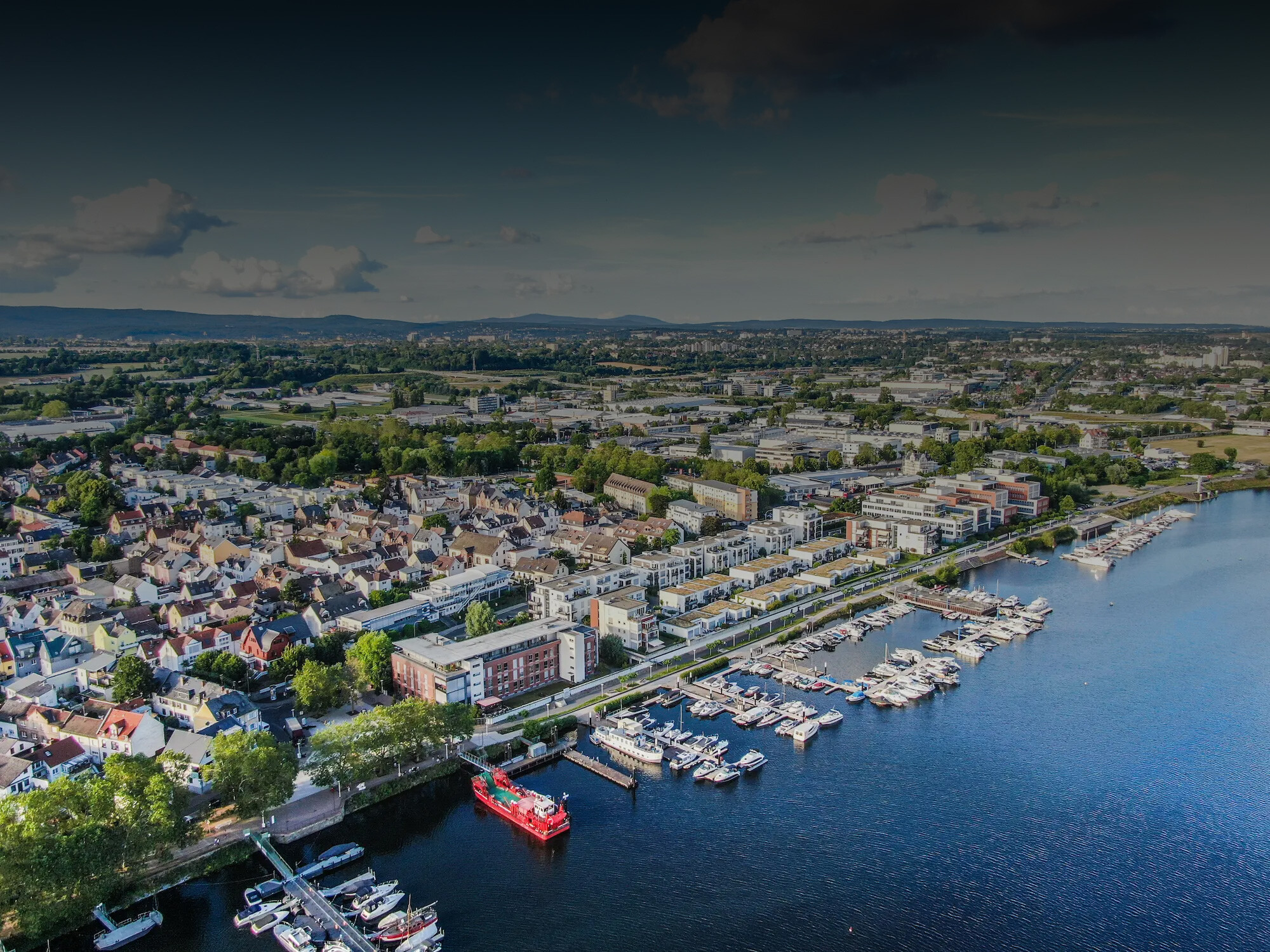 Stadt am Fluss mit Jachthafen, Booten und Häusern am Wasser.