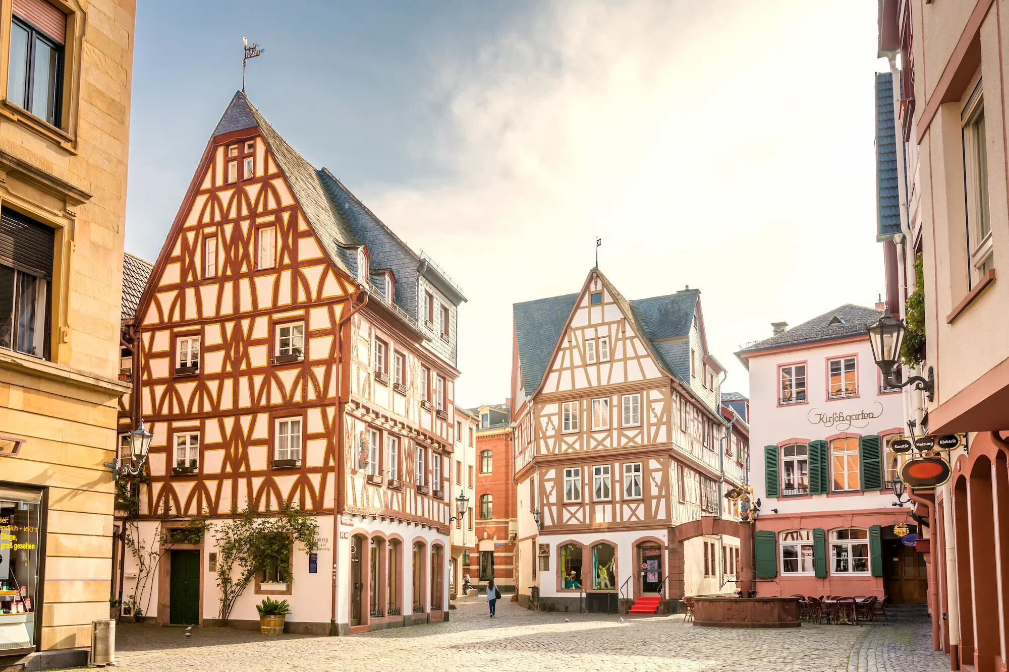 Fachwerkhäuser mit steilen Dächern an kopfsteingepflasterter Straße.