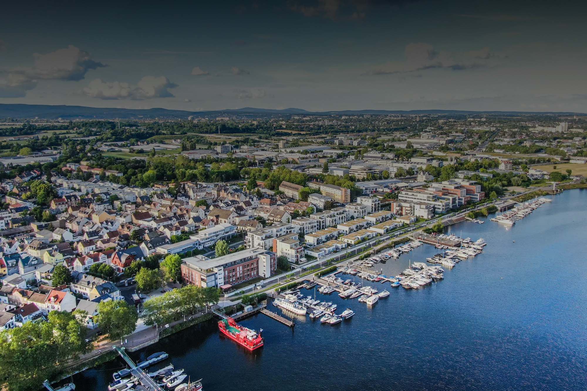 Stadt am Fluss mit Jachthafen, Booten und Häusern am Wasser.