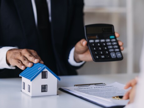 Makler hält Taschenrechner zur Immobilienbewertung