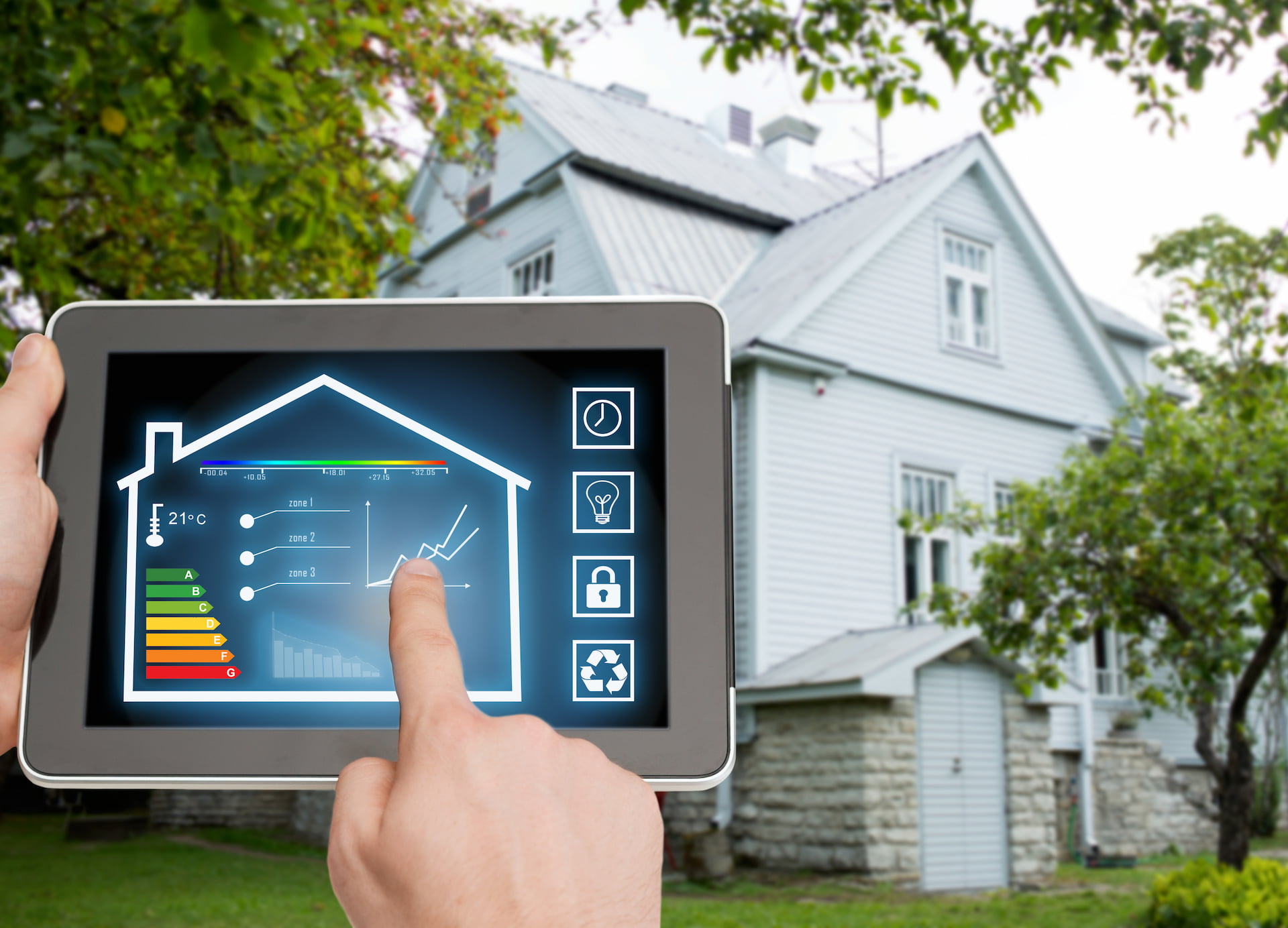 Hand steuert Smart-Home mit Tablet vor weißem Haus.