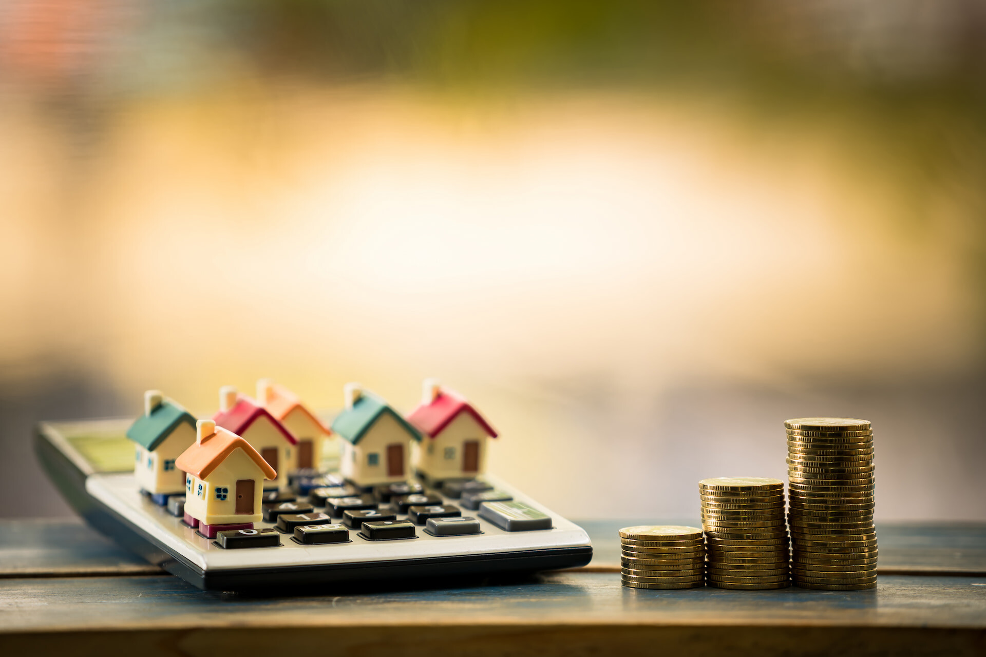 Mini-Häuser auf Rechner und Münzstapeln, Thema Immobilien-Investment.