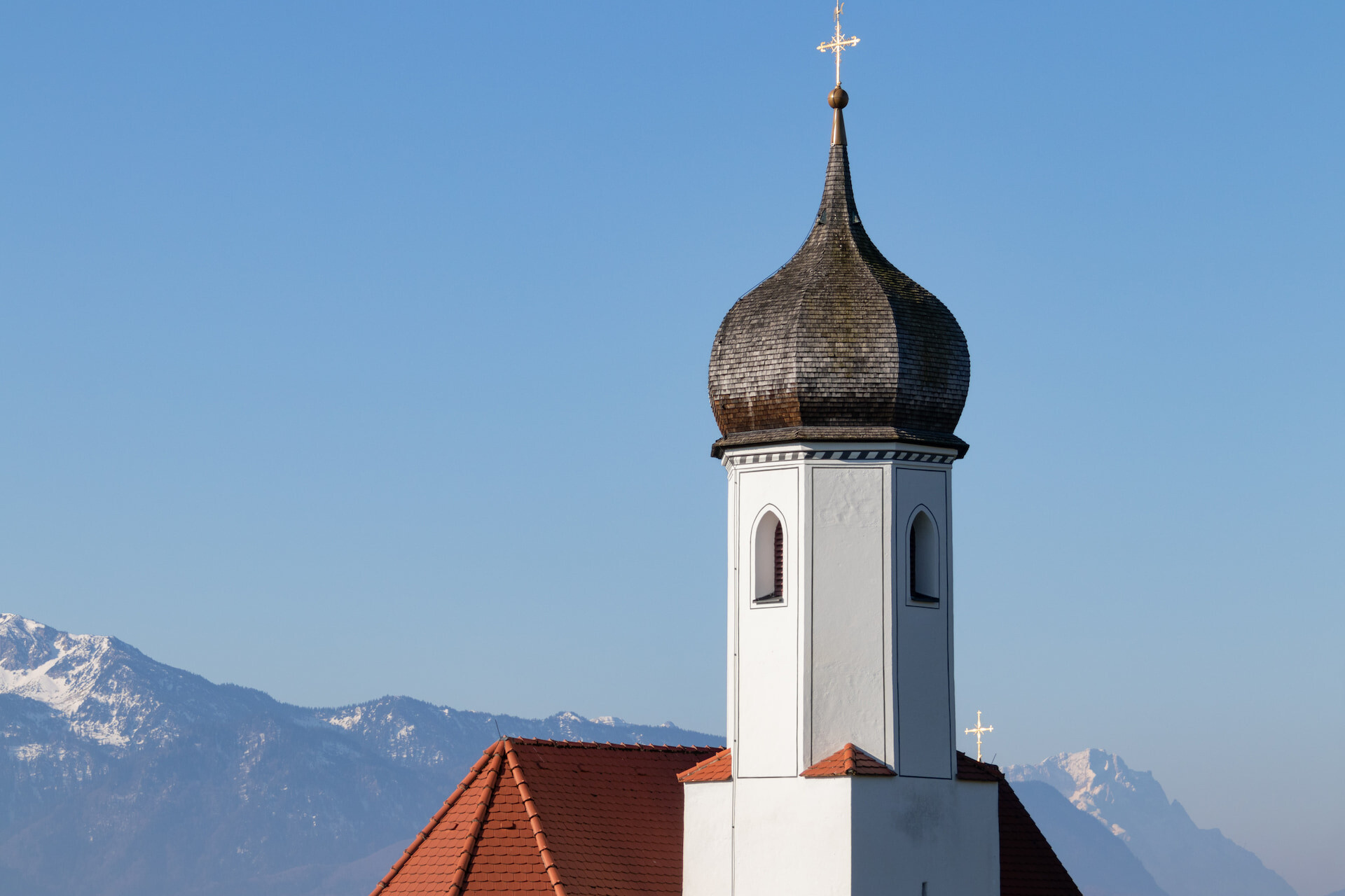 Weißer Kirchturm, Zwiebelkuppel, Berge, blauer Himmel.