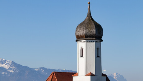 Weißer Kirchturm, Zwiebelkuppel, Berge, blauer Himmel.