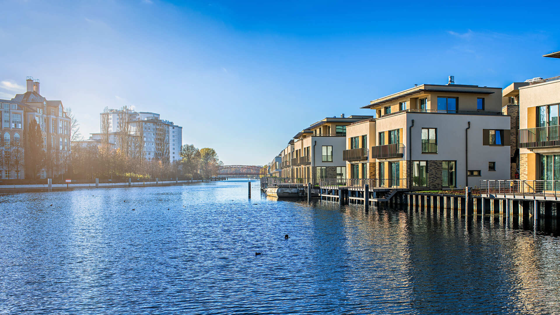 Waterfront Apartments am ruhigen Fluss bei blauem Himmel.
