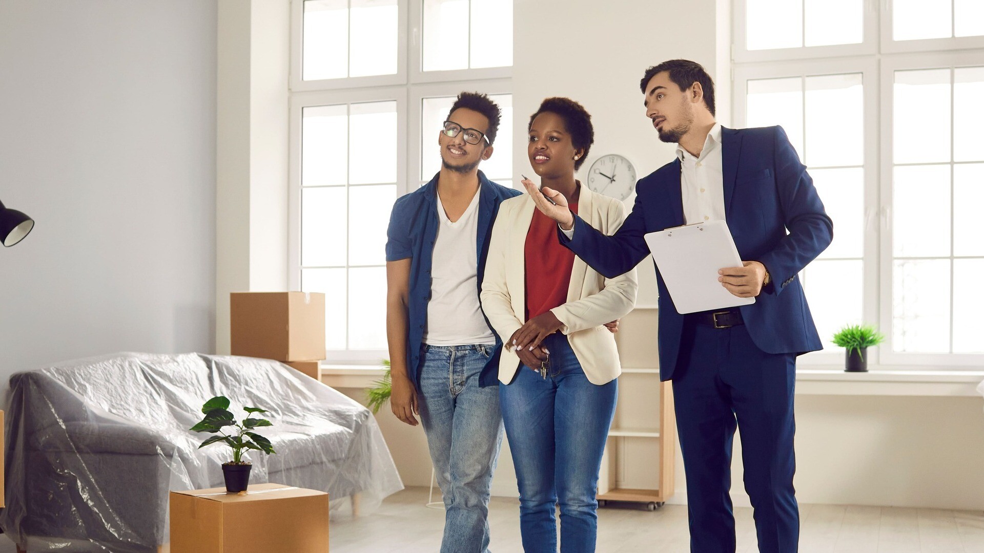 Paar besichtigt mit Makler ein helles Apartment.