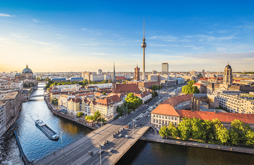 Berlin mit Fernsehturm, Fluss und Gebäuden bei blauem Himmel.