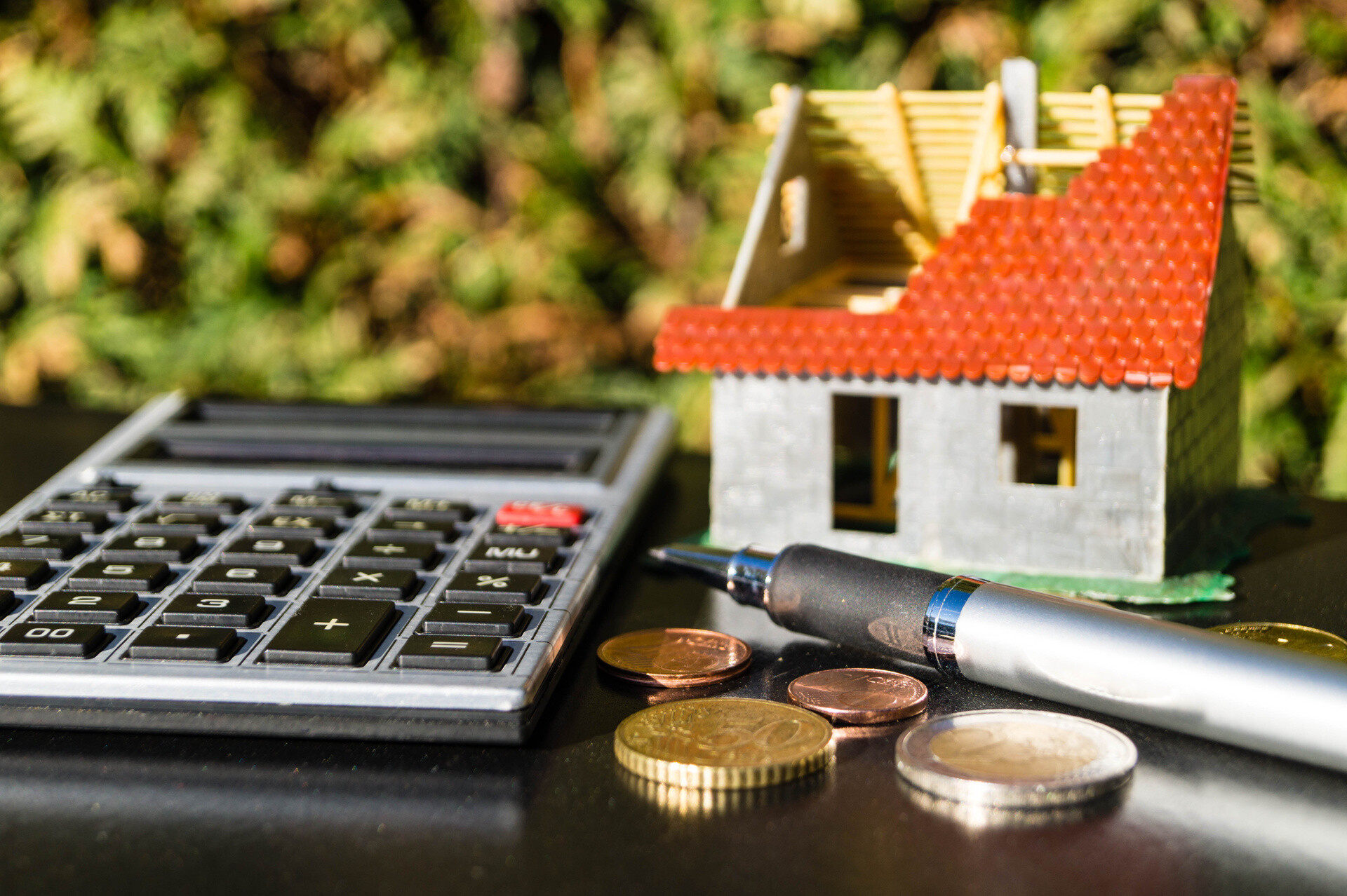 Modellhaus im Bau mit Taschenrechner und Münzen