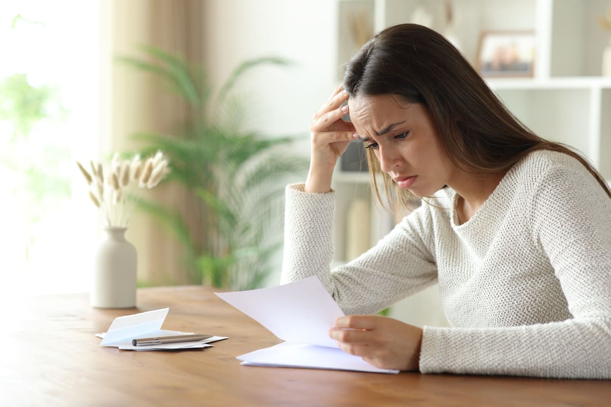 Frau liest besorgt Unterlagen am Tisch
