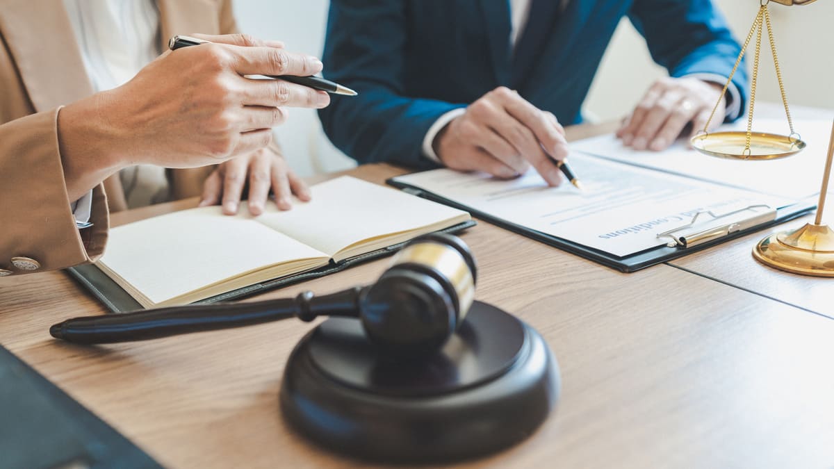 Richterhammer, Justitia-Waage und Anwälte bei Vertragsunterzeichnung