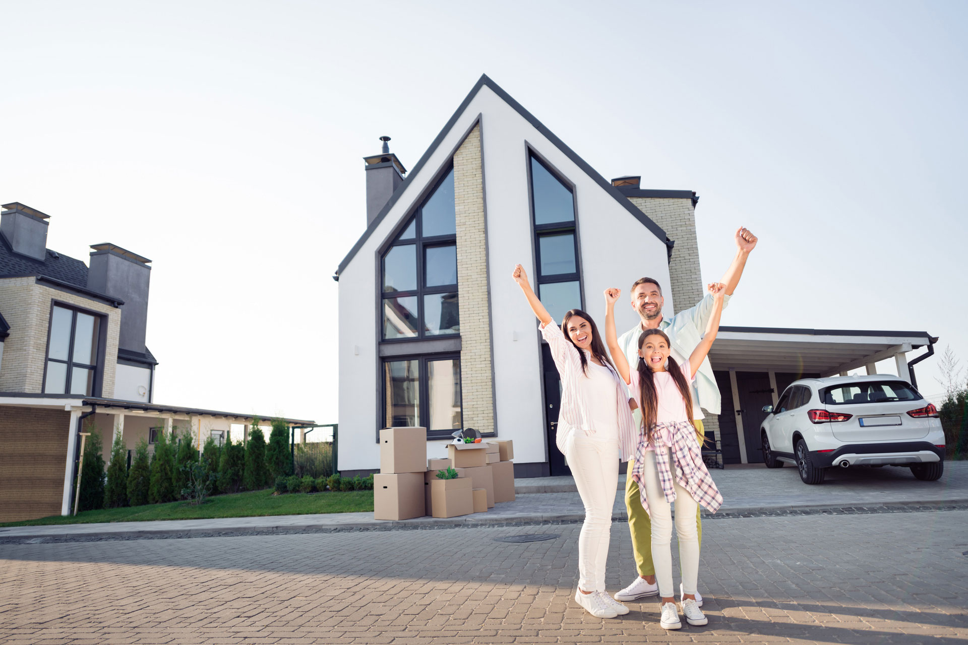 Familie jubelt vor dem eigenen Haus