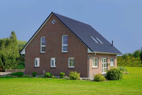 Geklinkertes Einfamilienhaus mit großem Garten als Symbol für den Immobilienverkauf