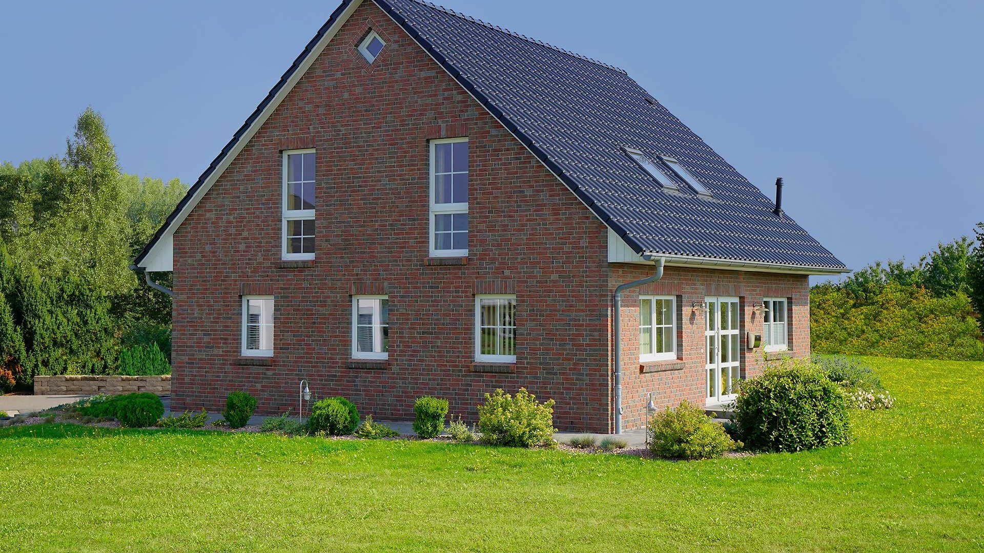 Geklinkertes Einfamilienhaus mit großem Garten als Symbol für den Immobilienverkauf