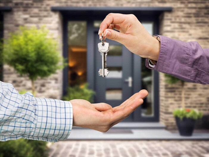 Schlüsselübergabe vor einem Haus als Symbol für Tipps beim Immobilienkauf