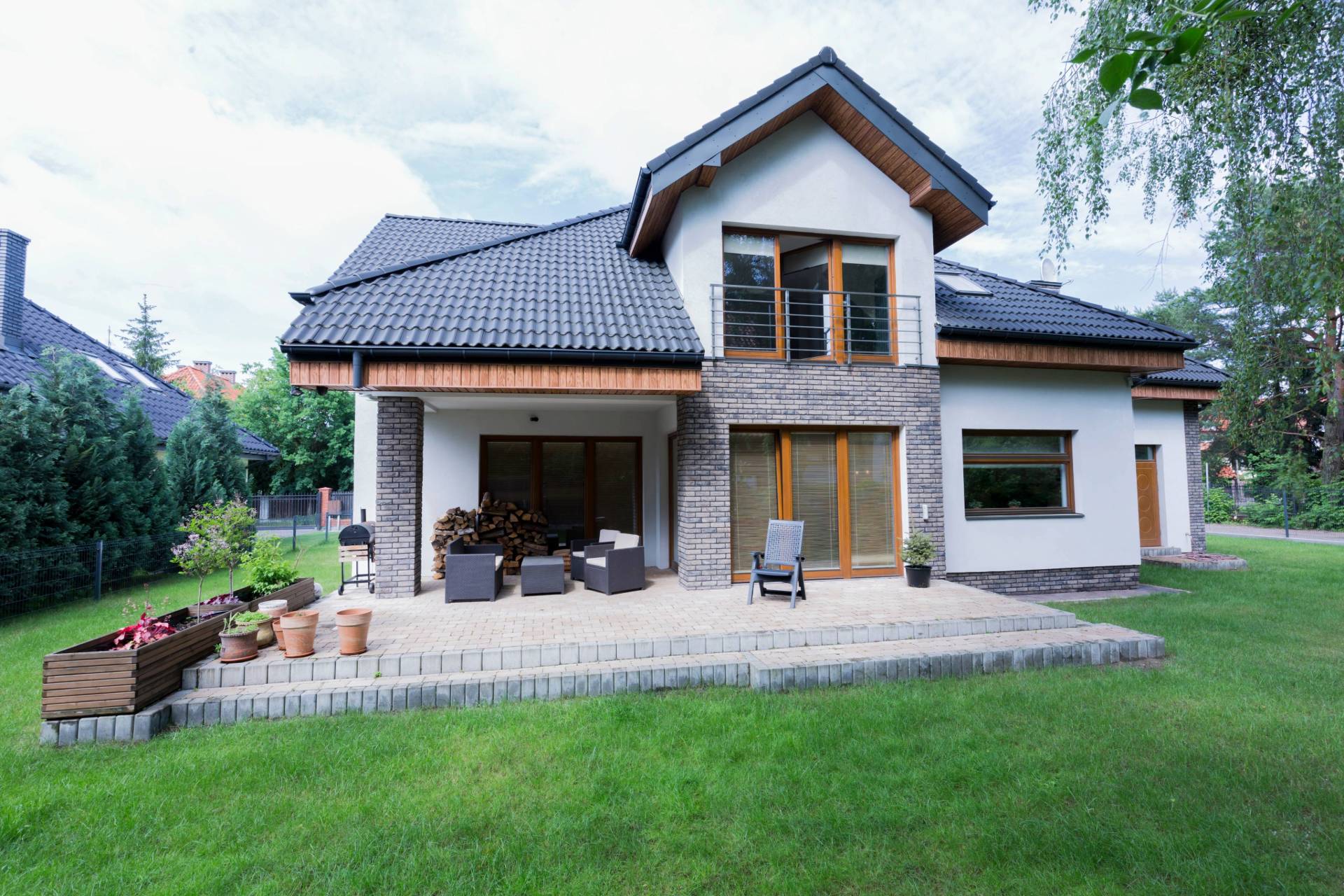 Modernes Einfamilienhaus im Landhausstil mit Steinfassade, großzügiger Terrasse und gepflegtem Garten.