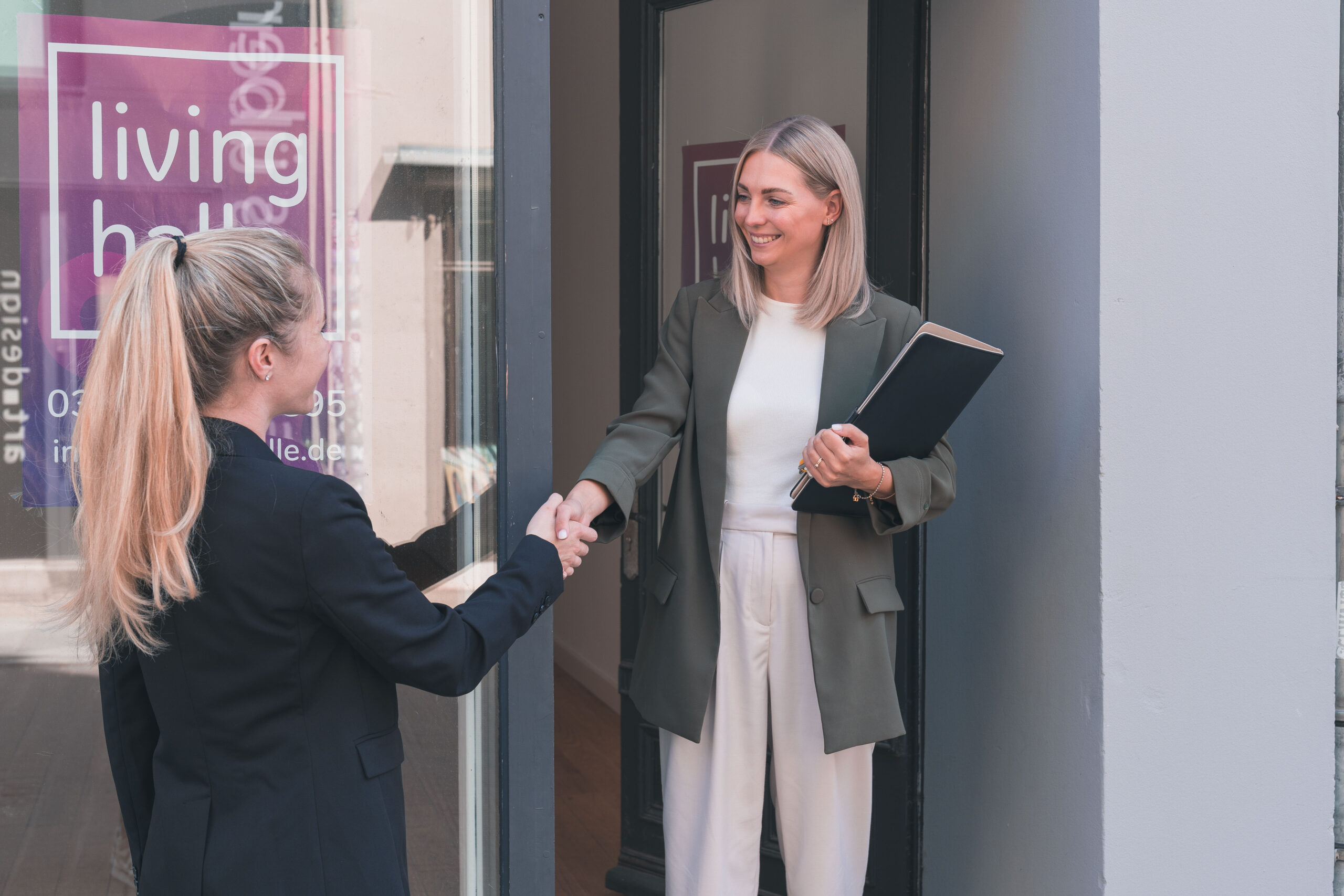 Zwei Frauen in Businesskleidung schütteln draußen die Hand.