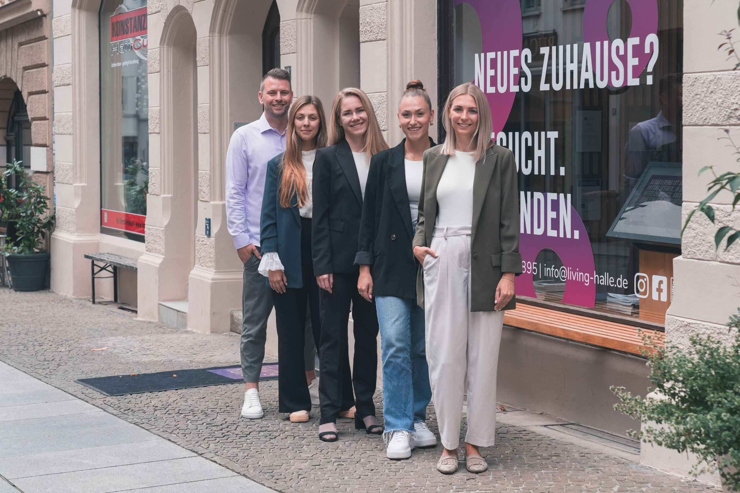 Das Team von living halle steht lächelnd vor Ihrem Schaufenster.