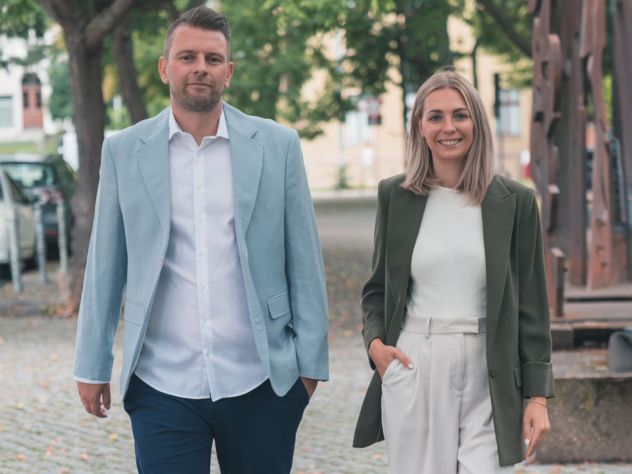 Christopher und Marika Oehlschlegel auf einem mit Bäumen gesäumten Kopfsteinpflasterweg.