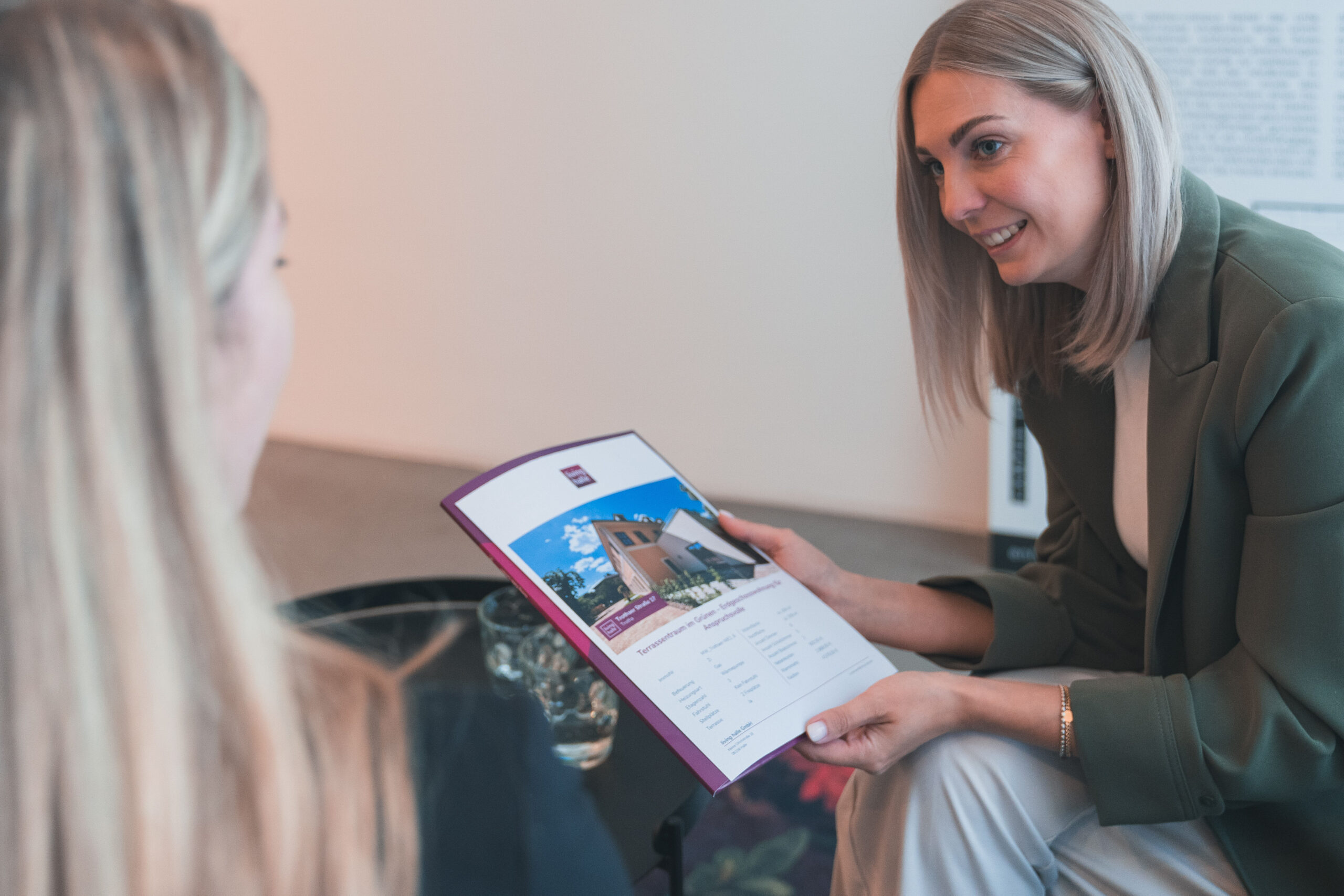 Zwei Frauen sehen sich gemeinsam eine Broschüre mit Gebäude an.
