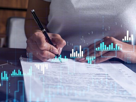 Unterzeichnende Person mit im Vordergrund eingeblendeten Finanztabellen.