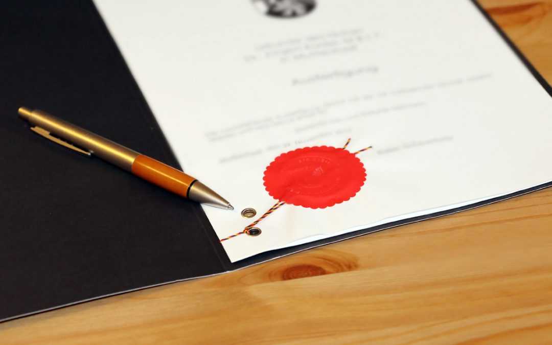 Dokument mit rotem Wachssiegel und Stift auf einem Holztisch, Kaufvertrag