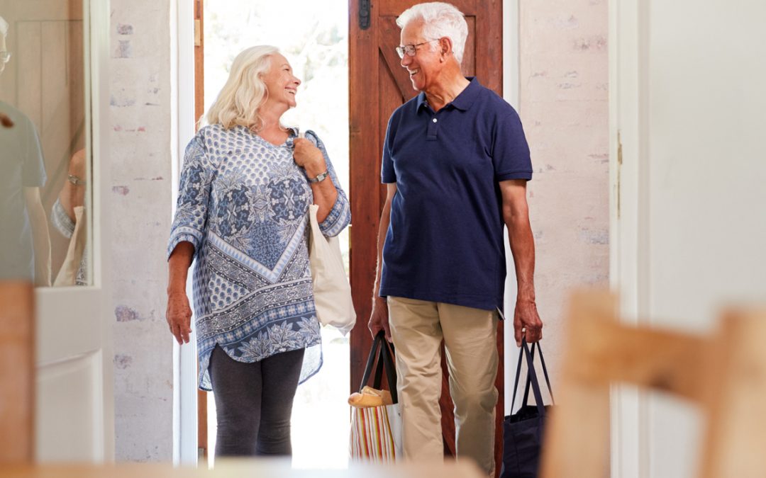 Älteres Paar mit Taschen betritt gemeinsam ein Haus, Eigentümer