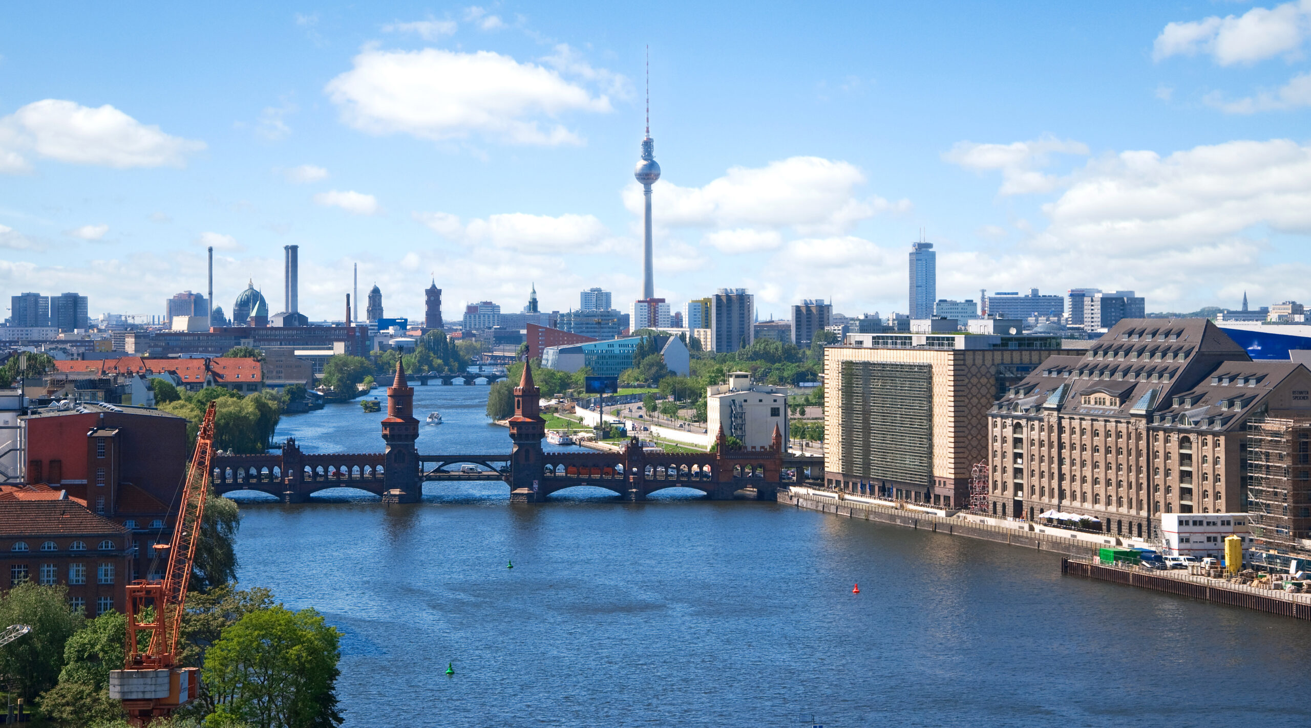 Berlin mit Spree, Oberbaumbrücke und Fernsehturm bei blauem Himmel.