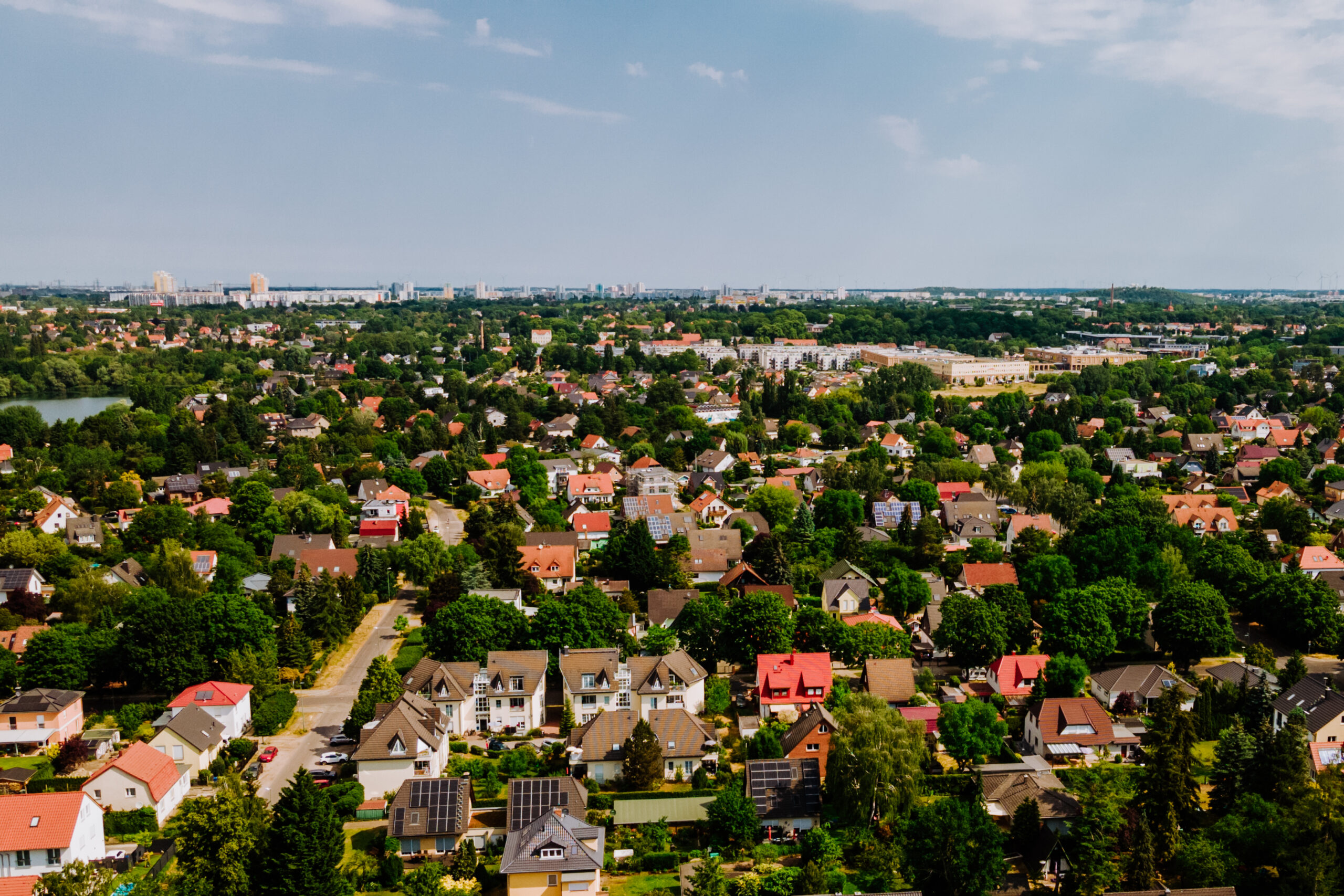 Vorort von Berlin mit Häusern, Bäumen und Grünanlagen unter bewölktem Himmel.