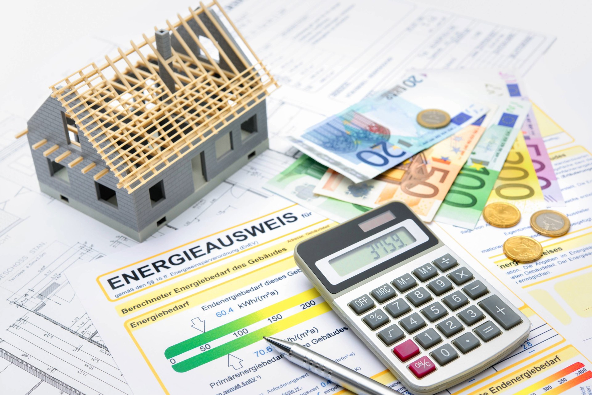 Modellhaus mit Euro-Scheinen, Taschenrechner und Energieausweis.