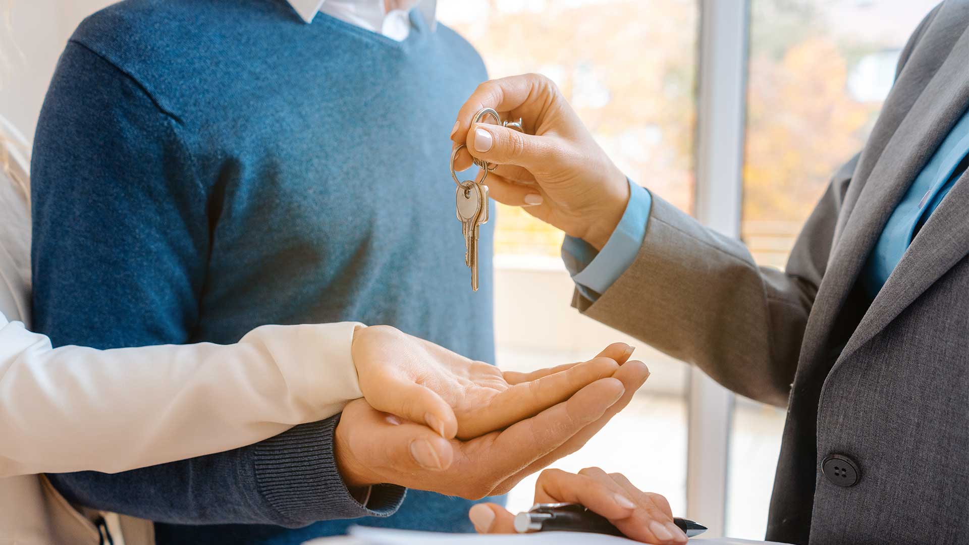 Übergabe des Hausschlüssels in die offene Hand einer anderen Person.