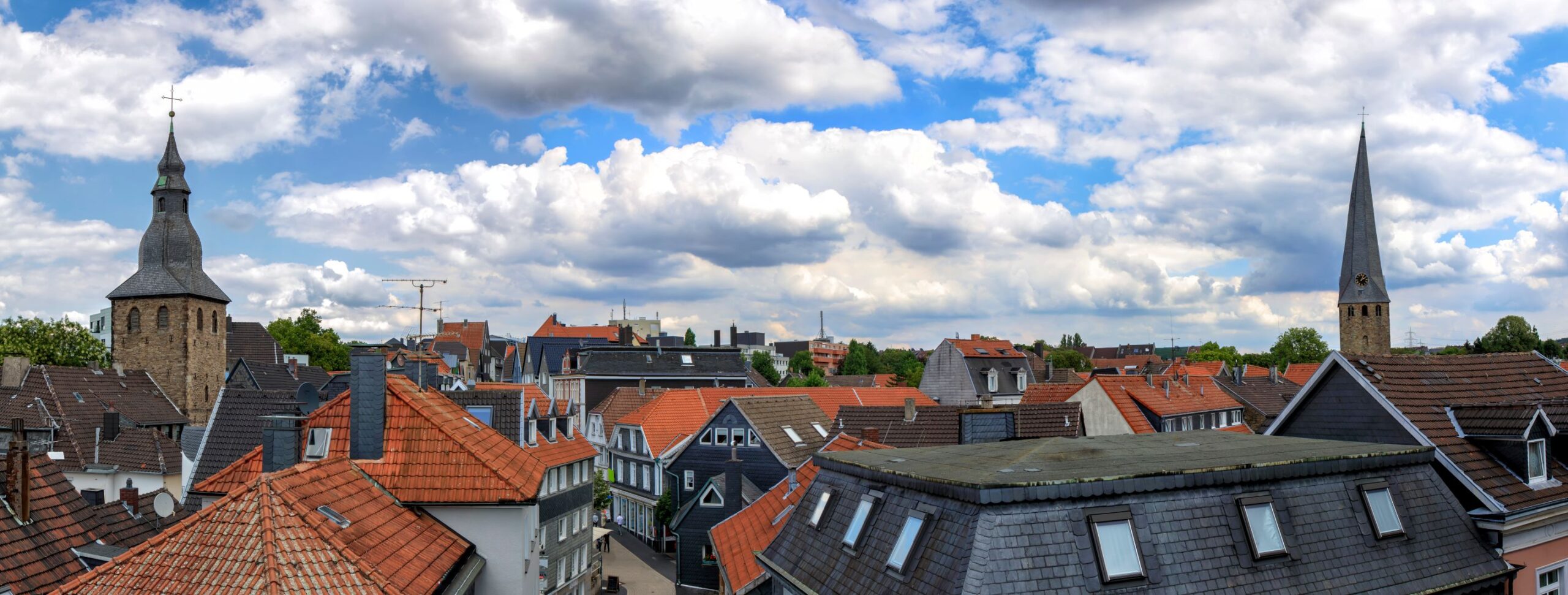 Stadt Hattingen mit roten Dächern, Kirchtürmen und teils wolkigem Himmel.