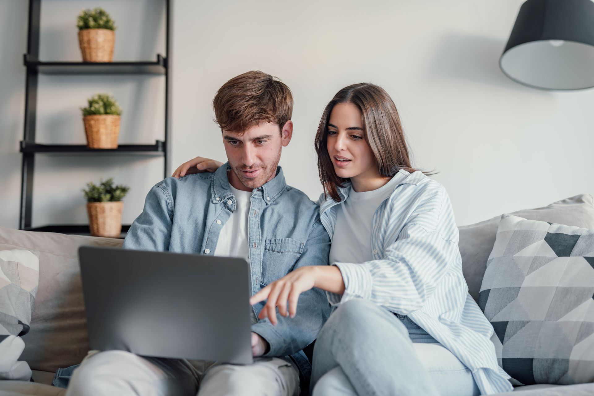 Paar auf Sofa schaut zusammen auf Laptop.