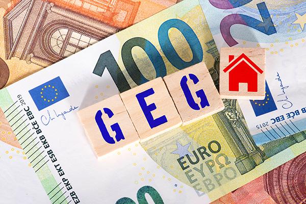 Euro-Scheine, Holzblöcke "GEG", rotes Haus-Icon obendrauf.