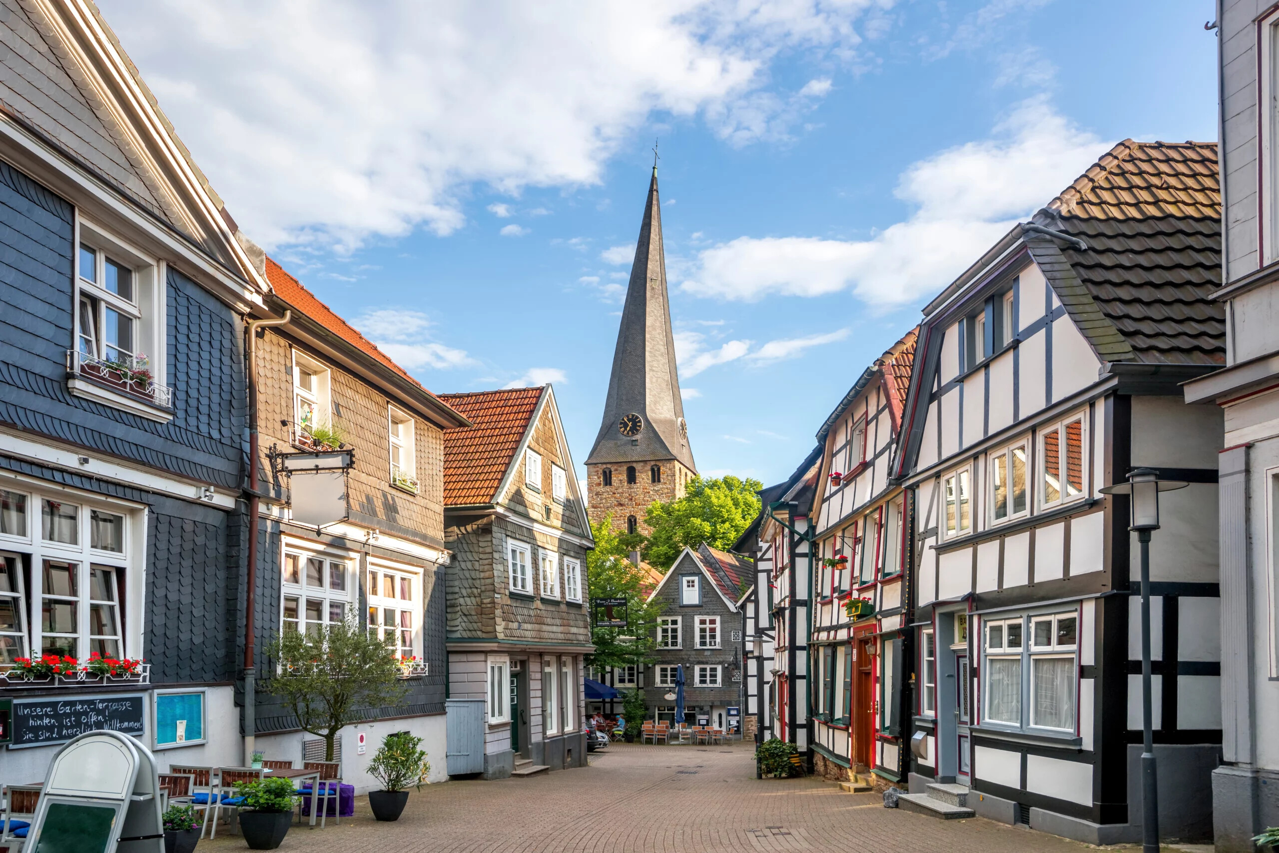 Malerische Gasse in der Altstadt von Hattingen mit Fachwerkhäusern und spitzem Kirchturm.