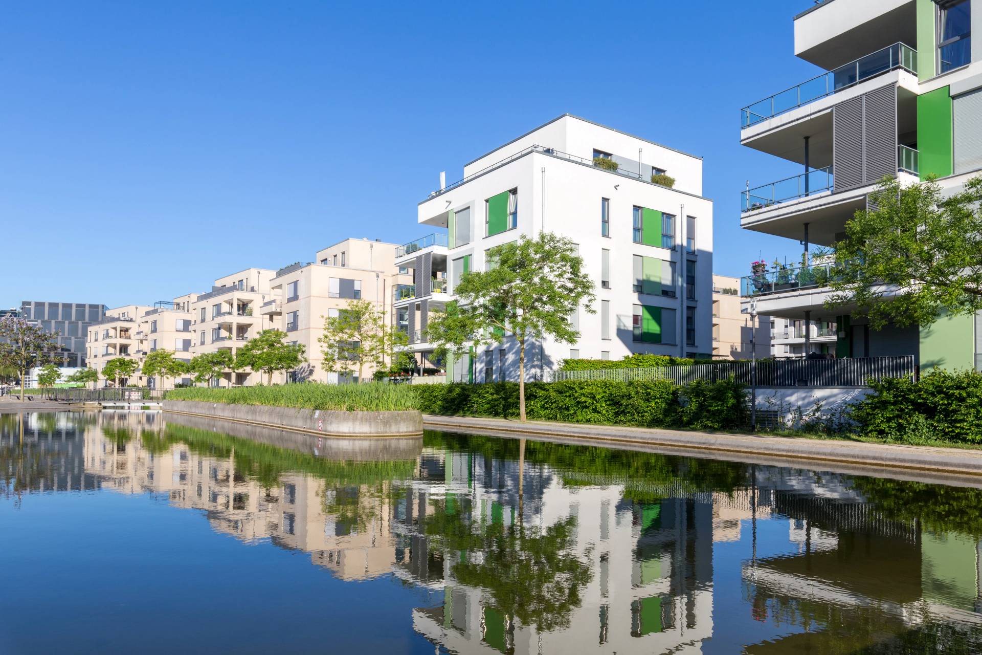 Wohnhäuser, die sich an einem sonnigen Tag in einem ruhigen Kanal spiegeln.