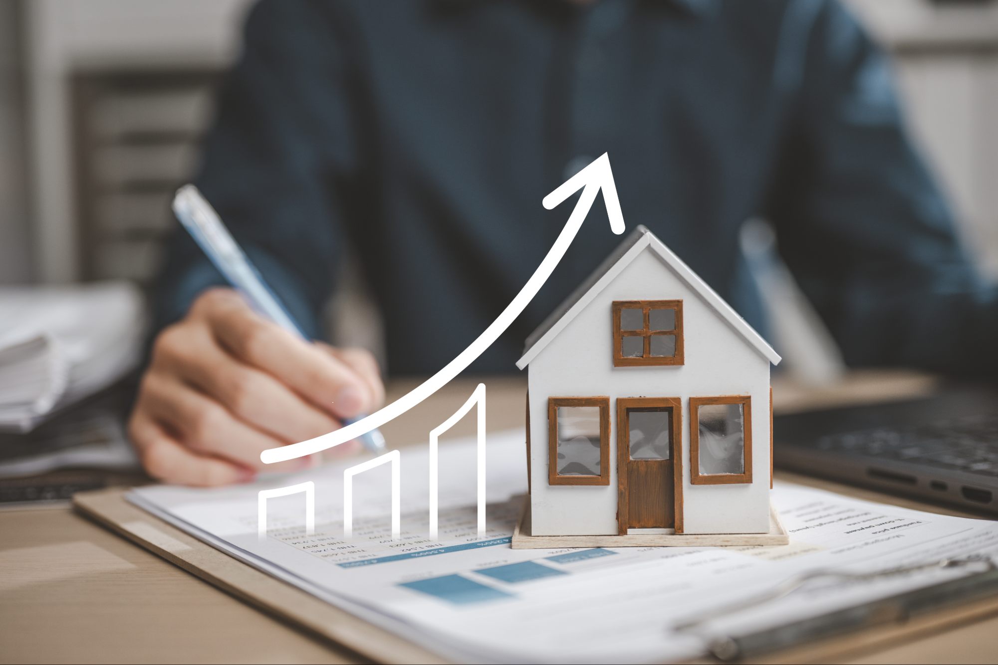 Person schreibt neben Modellhaus und Aufwärtsdiagramm.