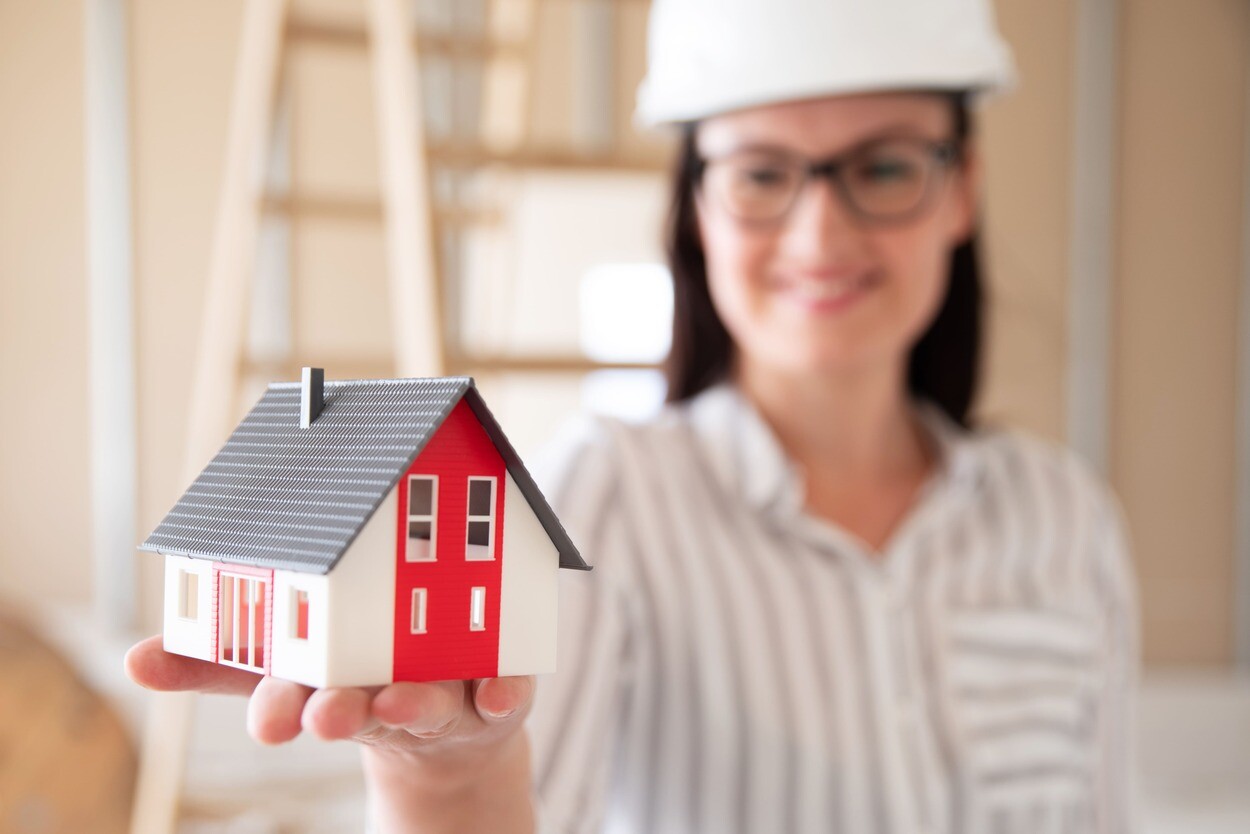 Frau hält Miniaturhaus