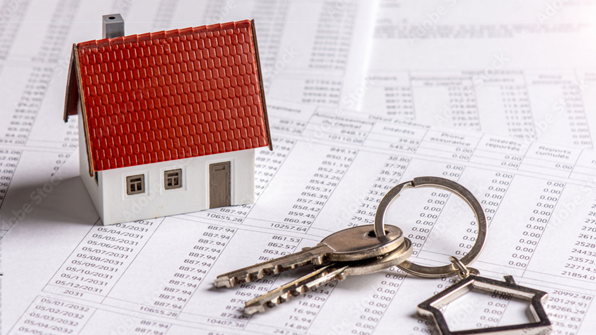 Musterhaus und Schlüssel auf Finanzpapieren mit Nummern und Daten.