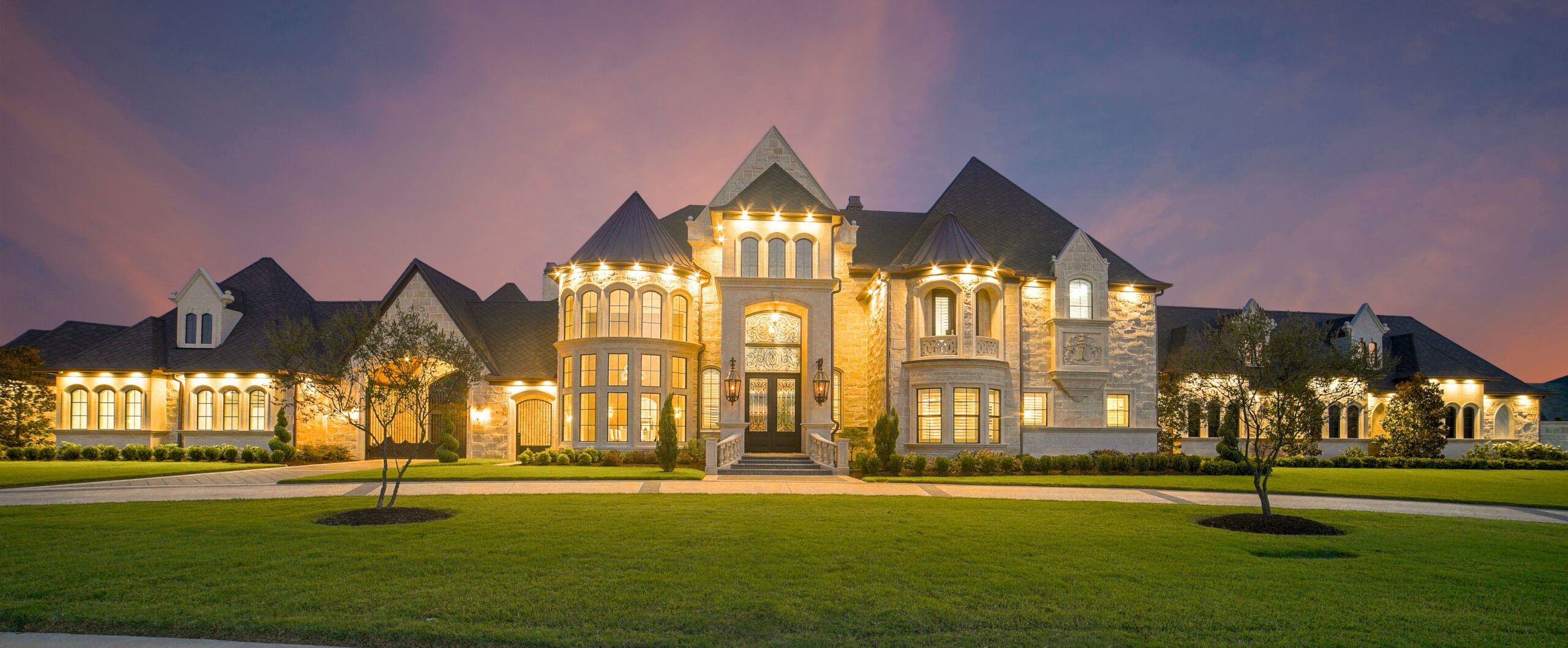 Steinvilla mit gepflegtem Rasen bei Sonnenuntergang.