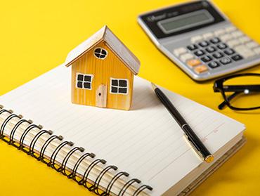 Ein Hausmodell aus Holz steht auf einem Notizblock