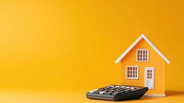 Ein Taschenrechner liegt vor einem Hausmodell