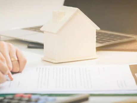 Eine Person unterzeichnet ein Dokument bei einem Immobilienmakler