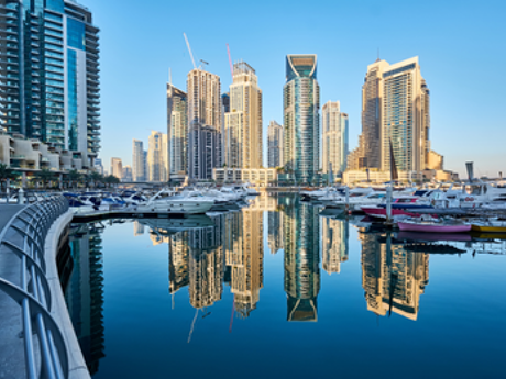 Wolkenkratzer und Yachten spiegeln sich im ruhigen Wasser der Dubai Marina.
