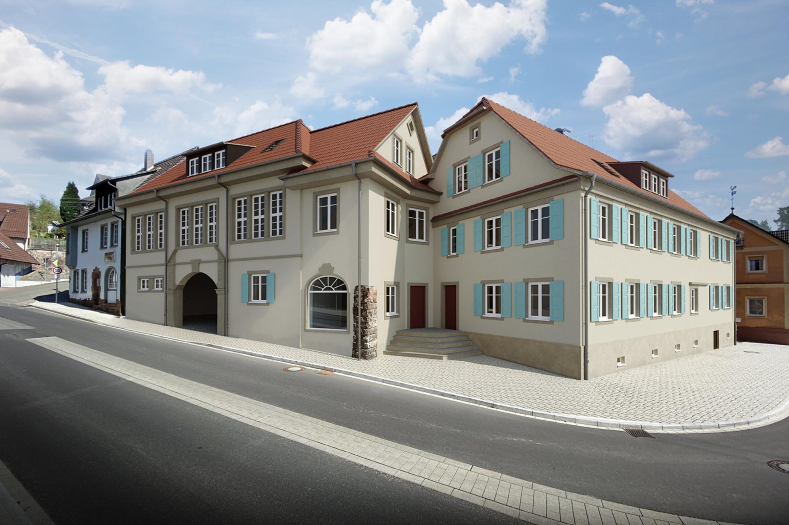 Zwei beigefarbene Gebäude mit roten Dächern an leerer Straße.