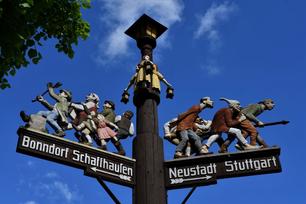 Bunte Wegweiser mit Figuren Richtung Bonndorf und Stuttgart.