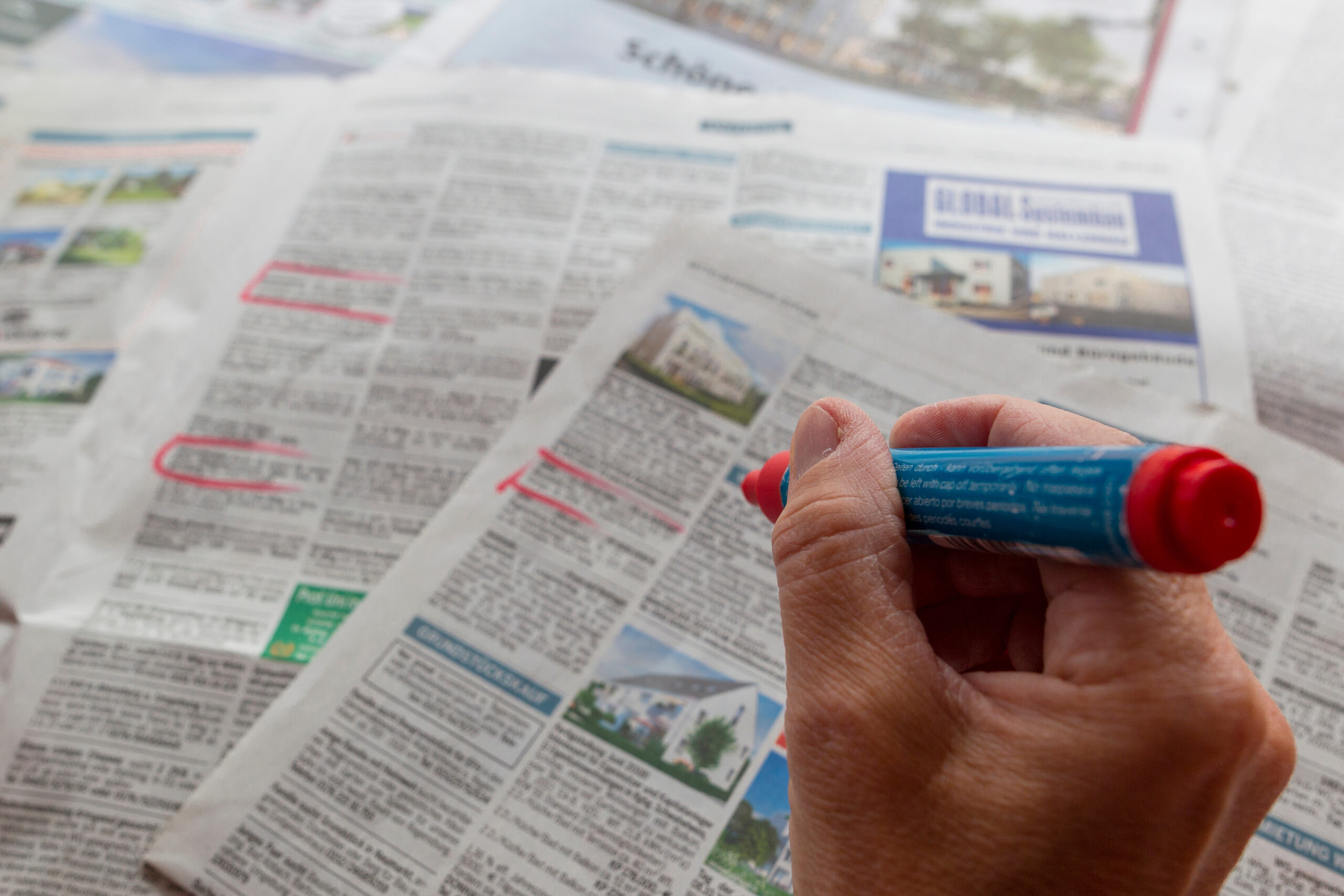 Person markiert Anzeigen in der Zeitung