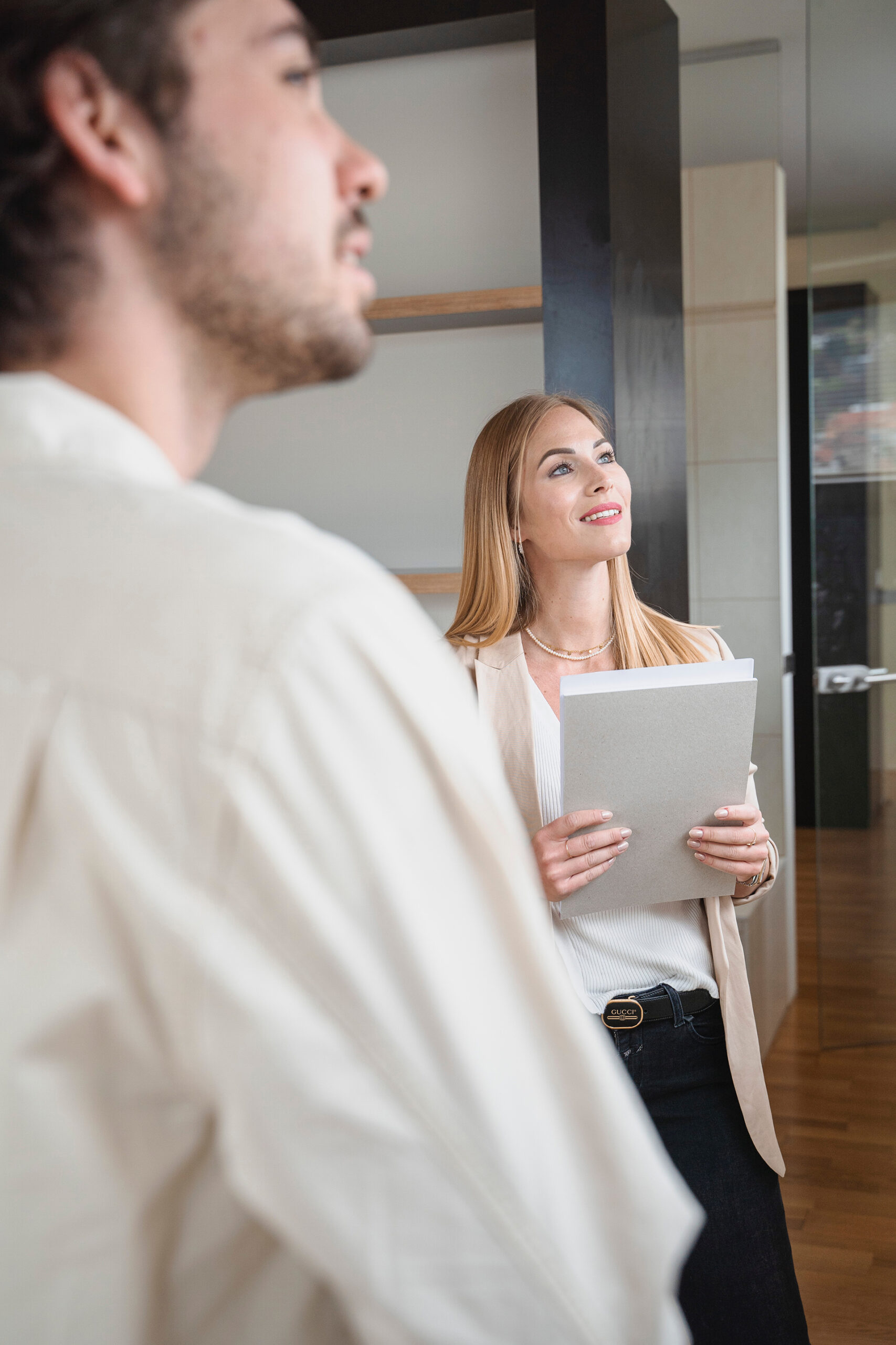 Frau mit Dokumenten lächelt, Mann im Vordergrund.