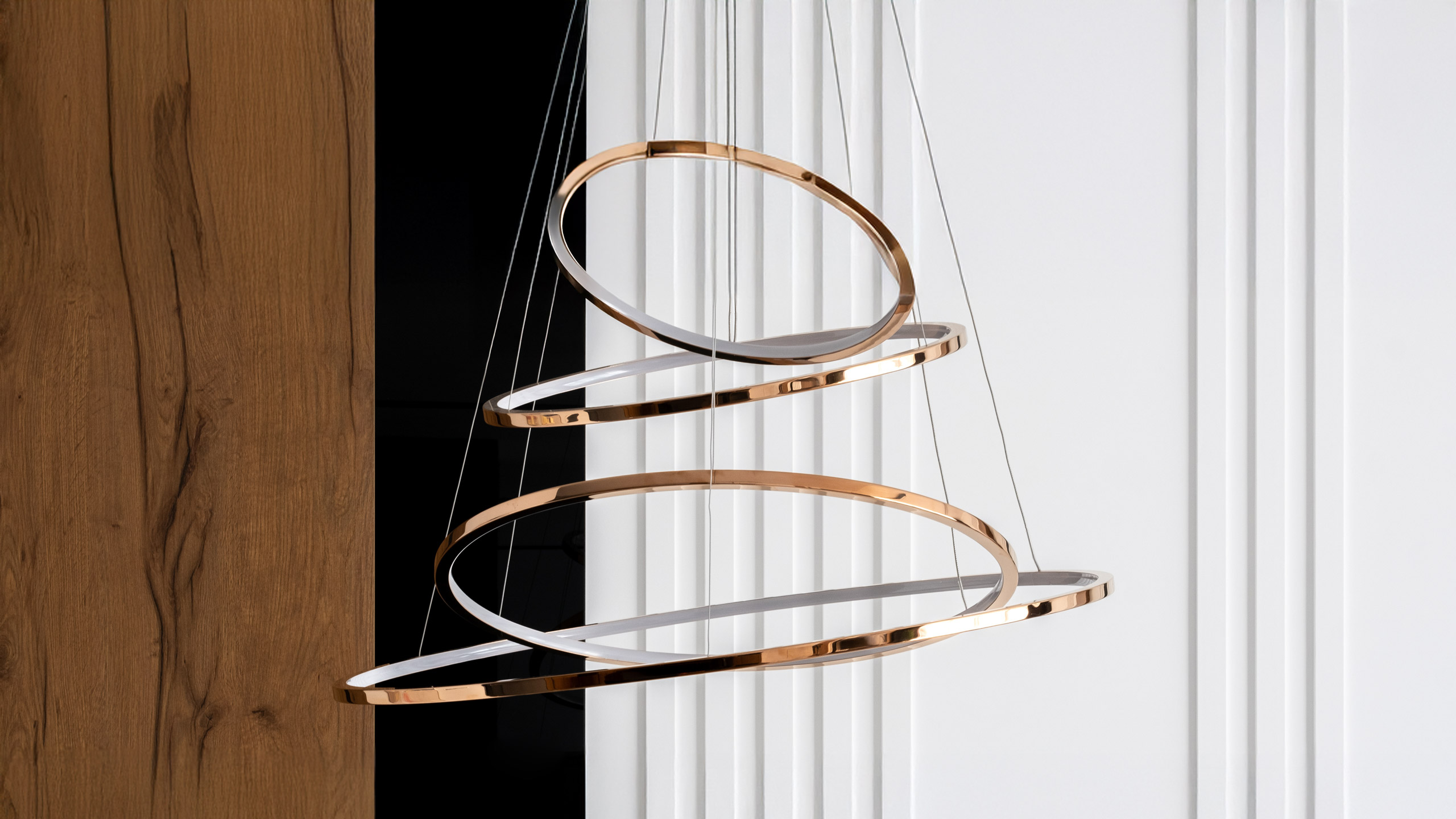 Goldene Pendelleuchte vor Holz- und weißen Paneelwänden.