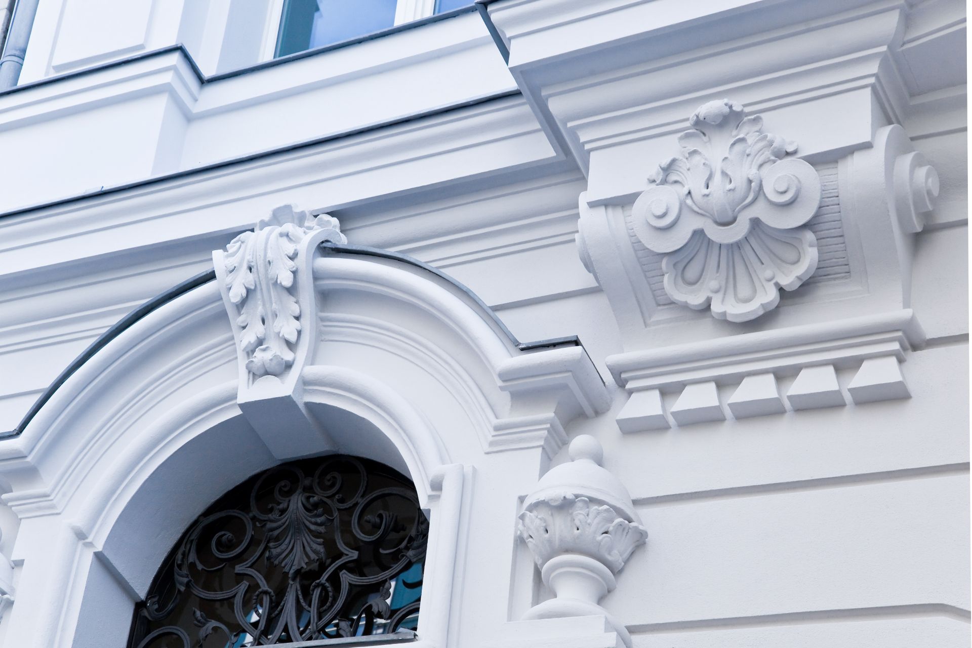 Weiße verzierte Fassade mit Reliefs und Fensterbogen.